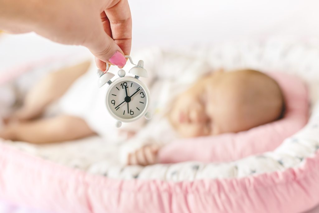 newborn baby and alarm clock. selective focus.