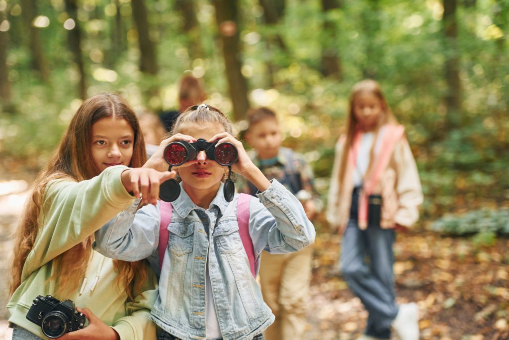 Front view of kids that is in green forest at summer daytime together