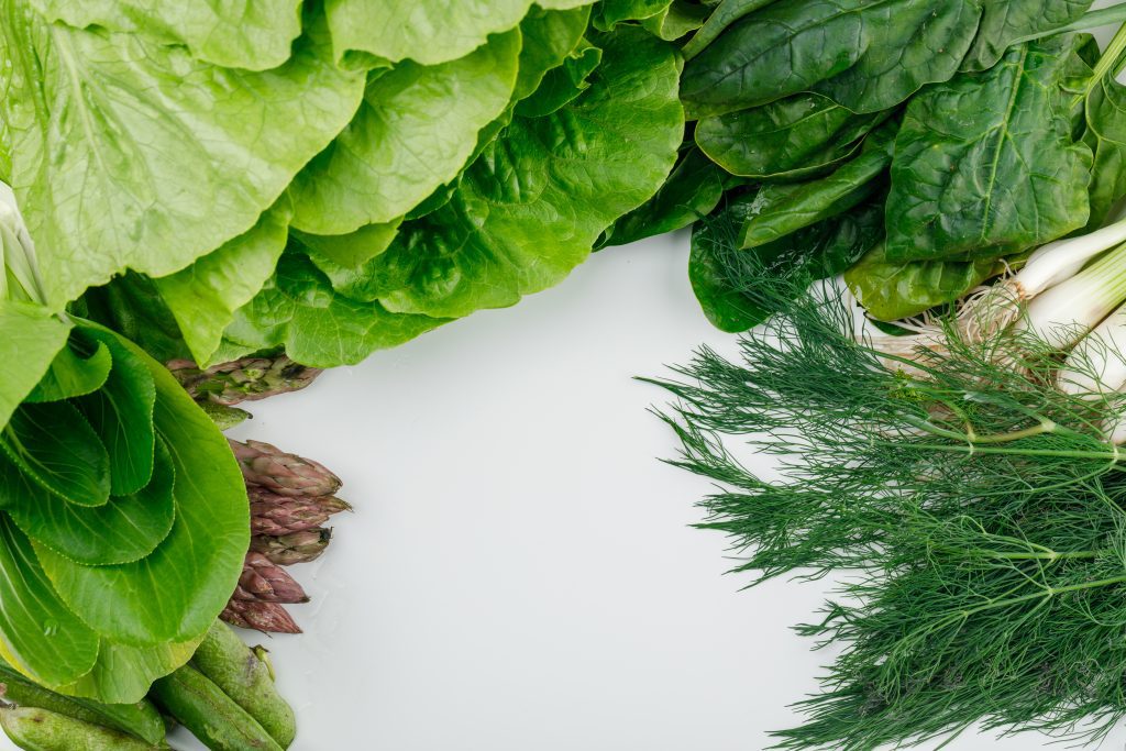 Lettuce with spinach, asparagus, sorrel, green onions and pods, dill high angle view on a white background