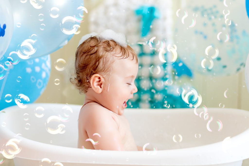 baby boy celebrates birthday 1 year in a bath with balloons, bathing baby with blue balloons