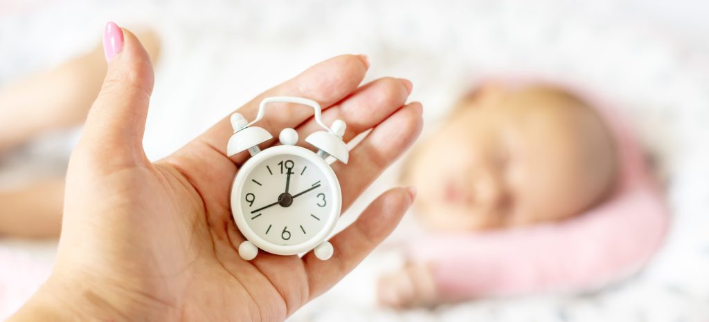 newborn baby and alarm clock. selective focus.