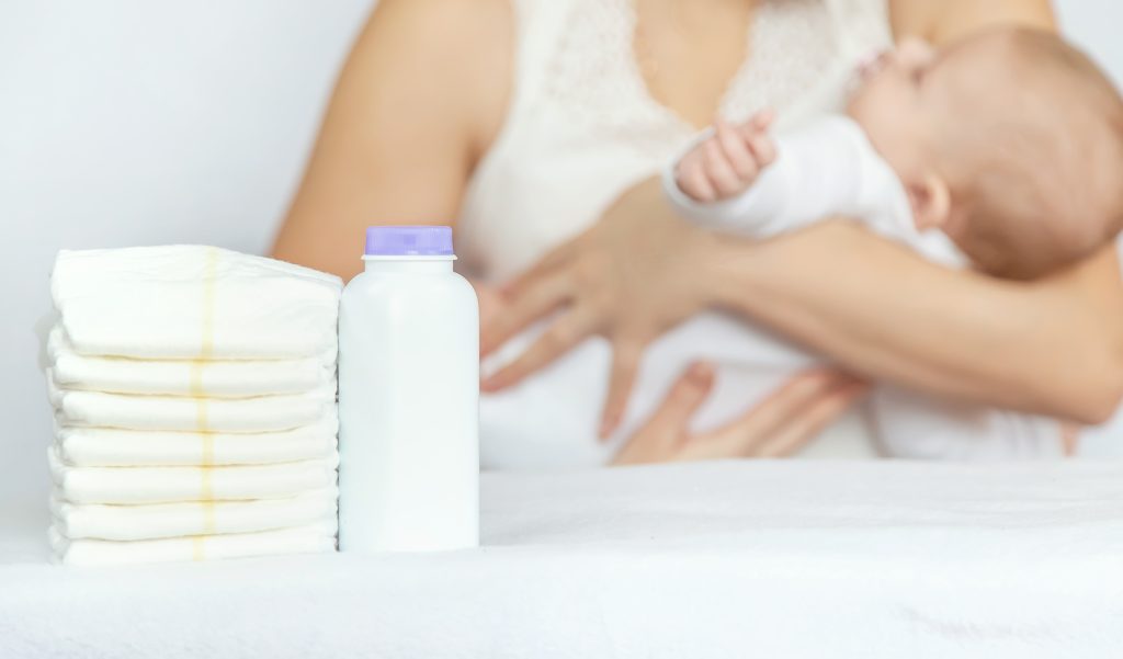 mother changes baby's diaper on a light background. Selective focus.